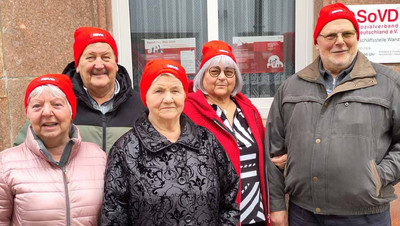 Eine Gruppe Frauen und Männer mit roten Mützen