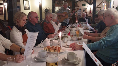 Menschen am Tisch mit Liedtexten in der Hand.