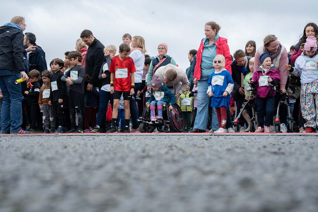 Eltern und Kinder stehen in einer Gruppe an der Startlinie.