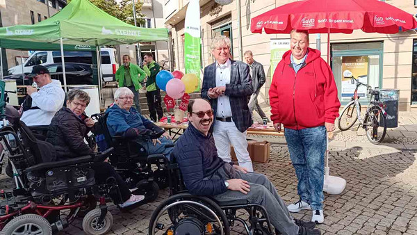 Rollstuhlfahrer*innen und stehend zwei Männer