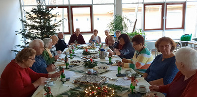 Mitglieder sitzen an festlich gedecktem Tisch, im Hintergrund ein Weihnachtsbaum